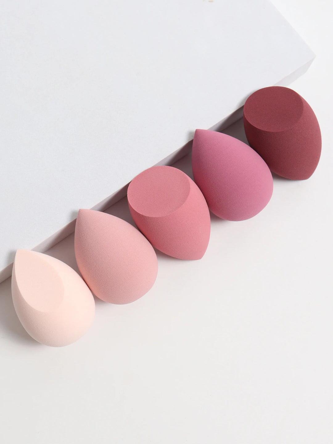 Bags of Beauty Eggs Makeup - Ensemble d'éponges de maquillage en différentes teintes sur fond blanc.