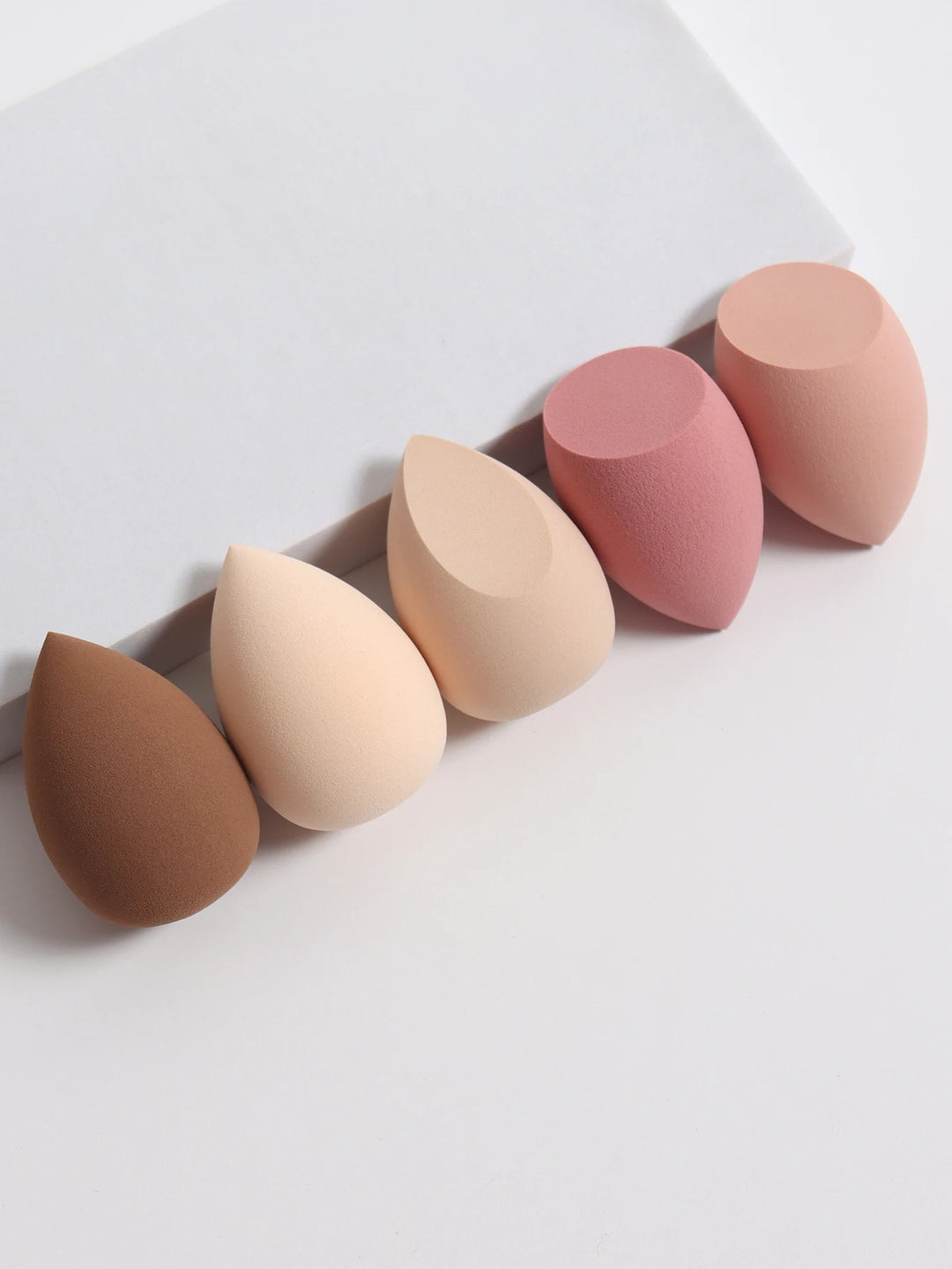 Bags of Beauty Eggs Makeup - Ensemble d'éponges de maquillage en différentes teintes sur fond blanc.