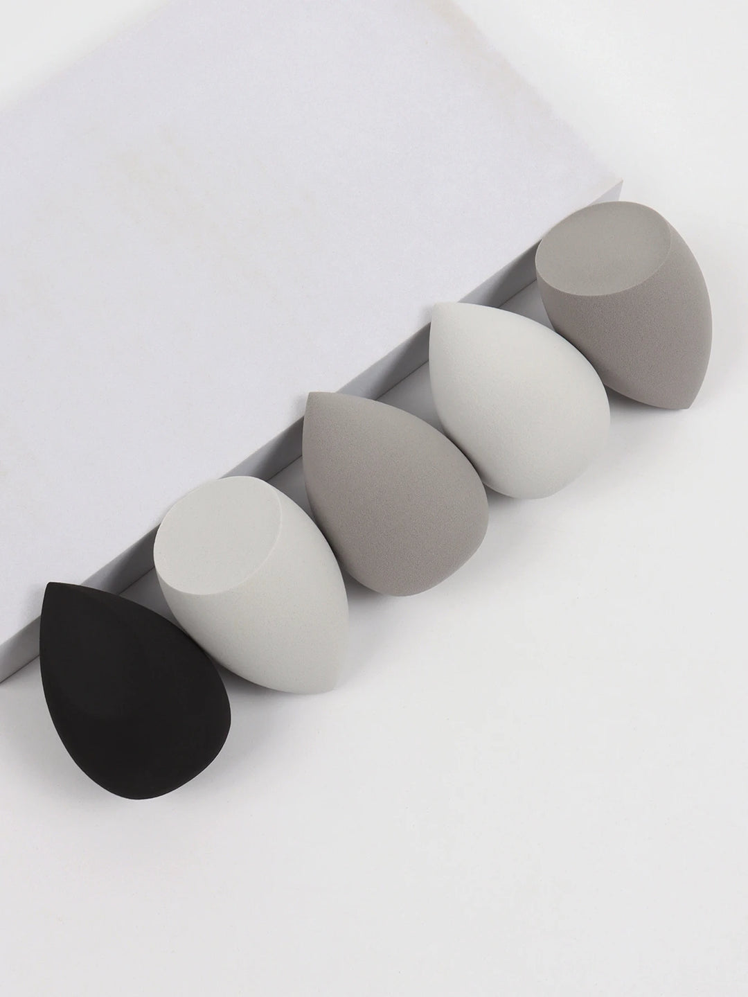 Bags of Beauty Eggs Makeup - Ensemble d'éponges de maquillage en différentes teintes sur fond blanc.